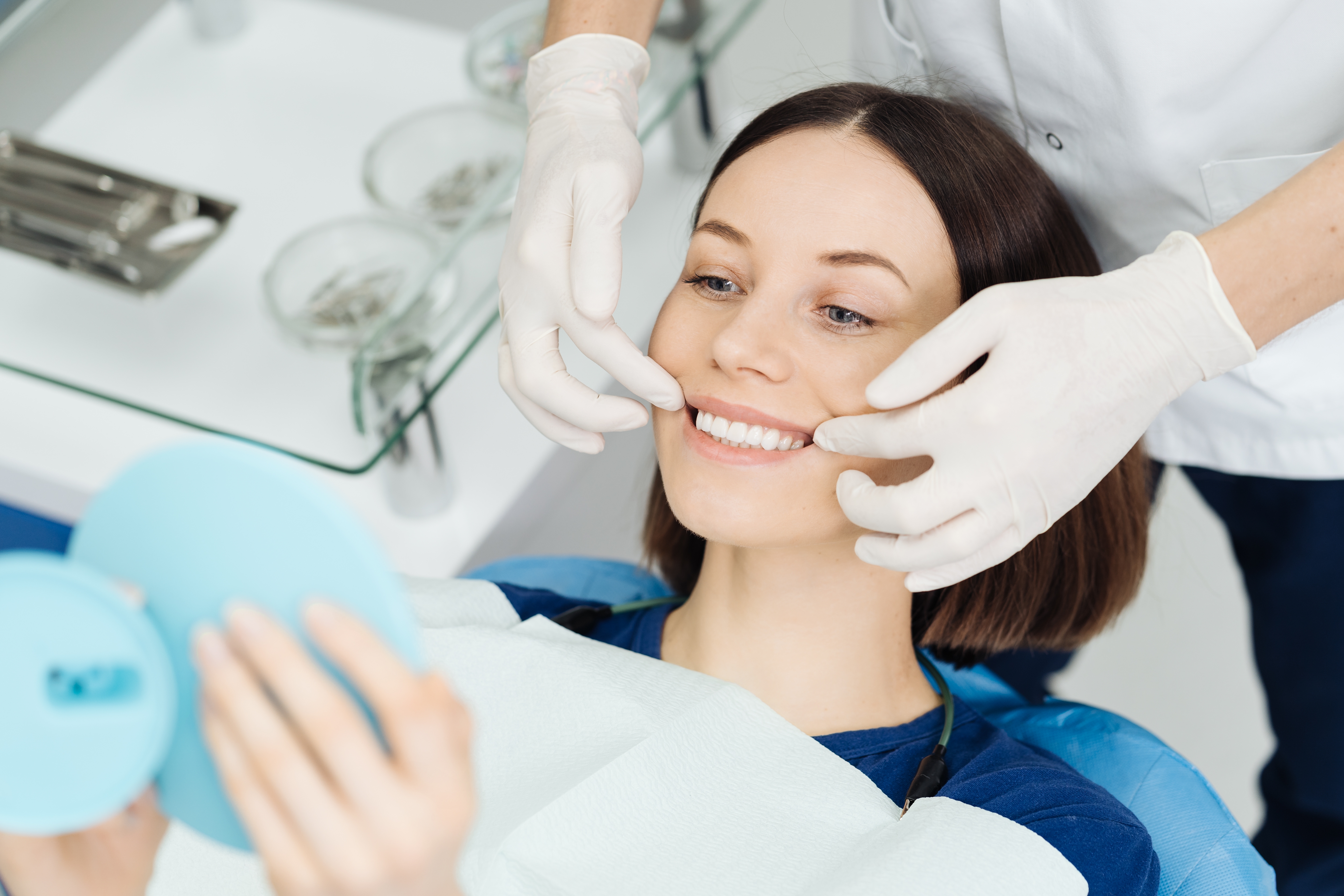 Look at me. Attractive caucasian lady checking her beautiful smile in mirror after stomatological treatment. Satisfaction of the visit stomatologist